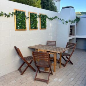 A wooden table and chairs on a patio at Casa del Mar - Huisie by die See in Langebaan