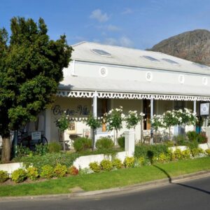 A white house with a mountain in the background at Centre-Ville Guest House in Franschhoek