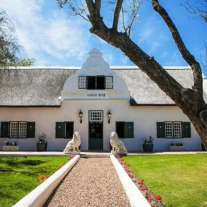 A white house with two dogs sitting in front of it at Champagne De Kleijne Bos Pty Ltd in Paarl