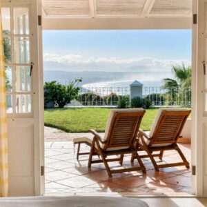 Two chairs on a patio with a view of the ocean at Clementine Cottage in Plettenberg Bay