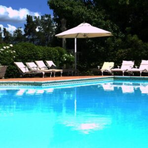 A swimming pool with chairs and an umbrella at Clos Malverne Wine Estate in Stellenbosch