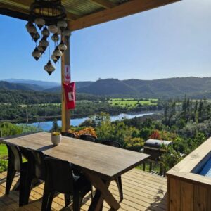 A wooden table and chairs on a deck with a swimming pool at Cloud 9 Estate - Chalet in Knysna