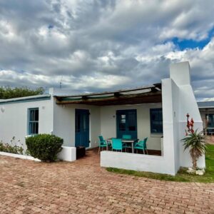 A white house with a table and chairs at Coast Cottages Langebaan in Langebaan