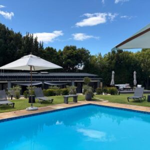 A swimming pool with chairs and an umbrella at Constantia Winelands Lodge in Constantia
