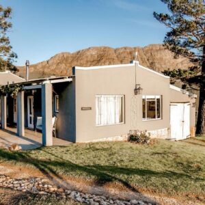 A white house on a hill with a fence at Courchevel Cottages in Franschhoek