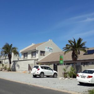 Two cars parked in a parking lot in front of a house at Croeso Guest House in Langebaan