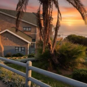 A house with a fence and a palm tree at Dana Bay Guesthouse in Dana Bay