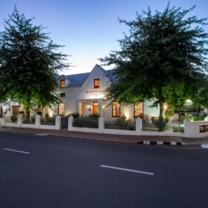 A white house with trees on the side of a street at De Hoek Manor in Stellenbosch
