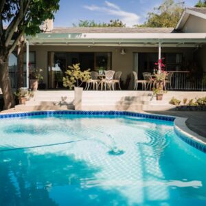 A swimming pool in front of a house at De Wingerd Wijnland Lodge in Paarl