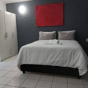 A bedroom with a large bed with a red painting on the wall at DigiStay in Simonʼs Town