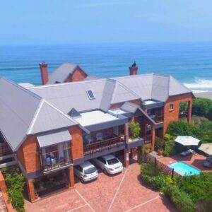 An aerial view of a house with cars parked in front at Dolphin Dunes Guesthouse in Wilderness