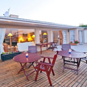 A patio with tables and chairs on a deck at Dolphins' Playground Beachfront B&B in Plettenberg Bay