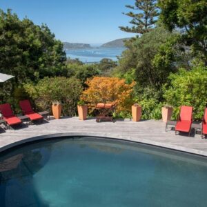 A swimming pool with chairs and a table and an umbrella at Double Dutch B & B in Knysna