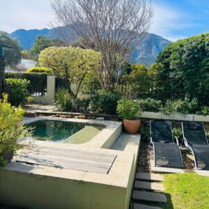A garden with a swimming pool and some benches at Eight on Tuin in Franschhoek