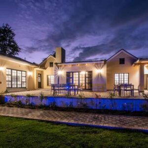 A large house with a patio at night at Eikenhof Estate in Brackenfell