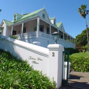 A white house with a green roof and a fence at Falcons View Manor in Knysna