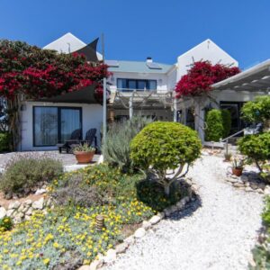 A house with flowers in the front yard at Farr Out Guest House in Paternoster