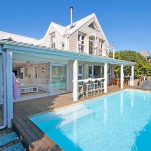A house with a swimming pool in front of a house at Fin Whale Beach House in Kommetjie