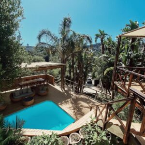 A swimming pool on a deck with a table and a table at Forest Nature Spa in Plettenberg Bay