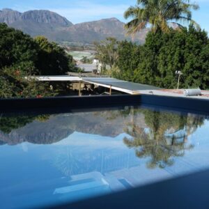 A swimming pool with mountains in the background at Foundation Stones Lodge in Paarl