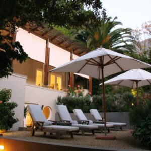 A group of chairs and umbrellas next to a building at Four Rosmead Boutique Guesthouse in Cape Town