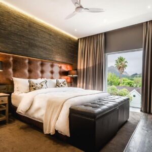 A bedroom with a large bed and a large window at Franschhoek Boutique Hotel - Lion Roars Hotels & Lodges in Franschhoek