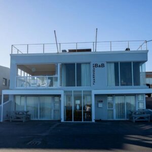 A blue building with glass doors in a parking lot at Franskraal Bed and Breakfast Pty Ltd in Franskraal