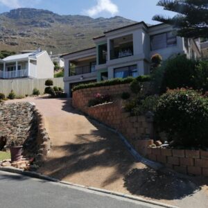 A house with a retaining wall and a driveway at Froggy at the Pond in Simonʼs Town