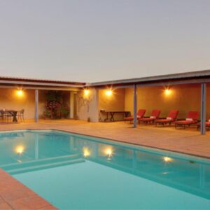 A swimming pool with chairs and a table on a patio at Gaikou Lodge in Swellendam