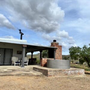 A brick house with a roof and a patio at Gamtoosberg Cottage in Oudtshoorn