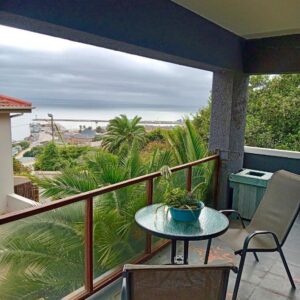 A balcony with a table and a view of the ocean at Gemma in Mossel Bay
