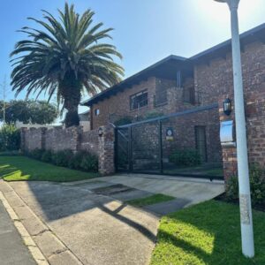 A brick building with a gate and a palm tree at Gigi At The Palm Tree in Plettenberg Bay