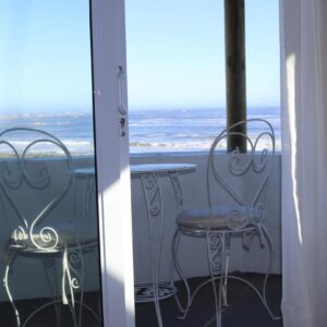 A table and chairs on a balcony with the ocean at Gilcrest Place Guest House in Paternoster