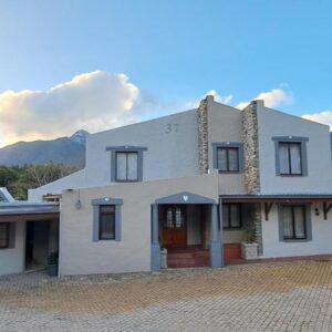 A white house with mountains in the background at Grace Walk Guest House in Swellendam