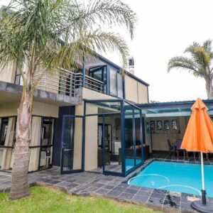 An orange umbrella next to a house with a swimming pool at Heathercreek Accommodation in George