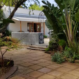 A house with a stone patio in front of a building at Hemel en Aarde Village Accommodation in Hermanus