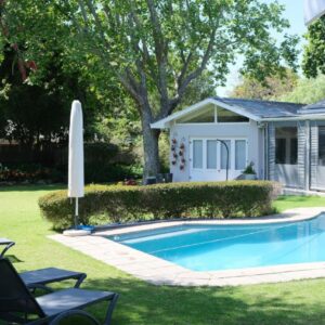 A swimming pool in a yard next to a house at High Hedges Guest Suites Constantia in Cape Town