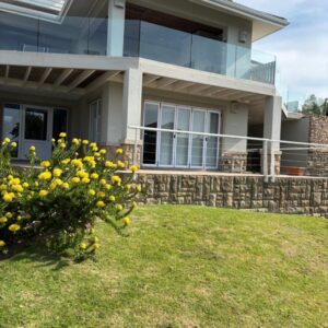 The guesthouse building above a garden of yellow flowers at Hill Top Guesthouse in Plettenberg Bay