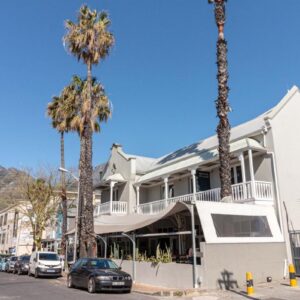 A white house with palm trees on a street at Hippo Boutique Hotel in Cape Town