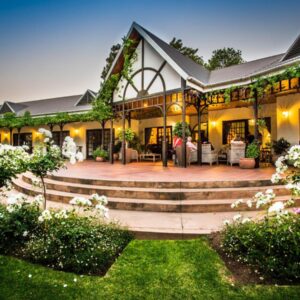 A large house with a patio and stairs at Hlangana Lodge in Oudtshoorn