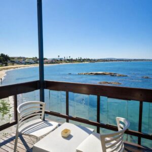Two chairs and a table on a balcony with the ocean at Hoedjiesbaai Hotel in Saldanha
