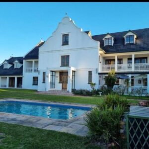 A large white house with a swimming pool in the yard at Hoekplasie Guesthouse in Mossel Bay