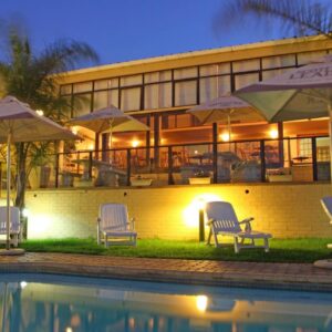 A group of chairs and umbrellas next to a pool at Hotel Portao Diaz in Mossel Bay