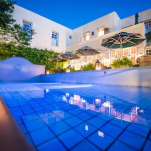 A swimming pool in front of a hotel at night at Hout Bay Manor in Hout Bay