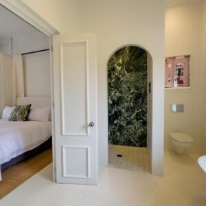 A white guest room with a bed and an open en-suite bathroom at Huguenot House in Franschhoek