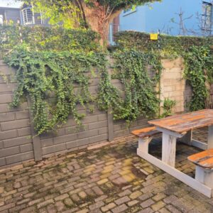 A wooden picnic table sitting in front of a brick wall at In Vrede in George