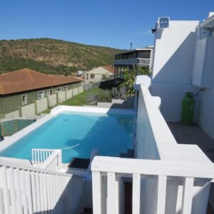 A view of a swimming pool with a white fence at Island View Rooms in Mossel Bay