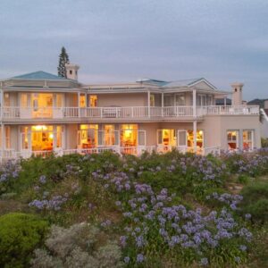 A large house on a hill with purple flowers at Isola Bella Guest House in Knysna