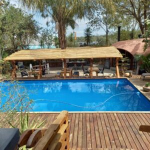 A swimming pool with a wooden deck and a picnic table at Karoozin Village in Oudtshoorn