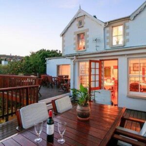 A deck with a wooden table and chairs on a balcony at Knysna Manor House in Knysna